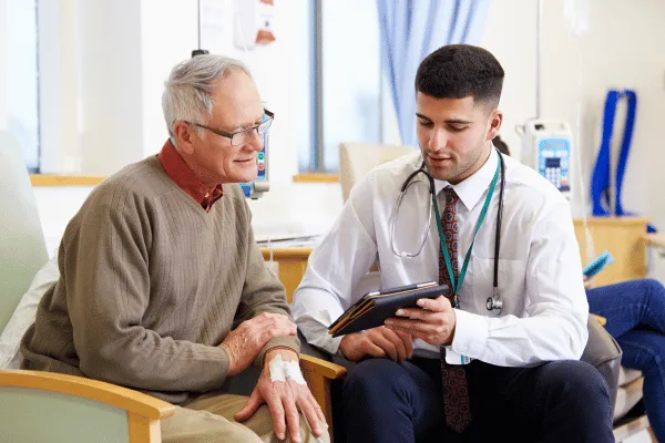 Médecin échangeant avec un patient âgé, une tablette à la main