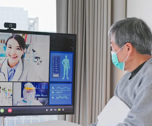 Téléconsultation sur grand écran avec un patient masqué